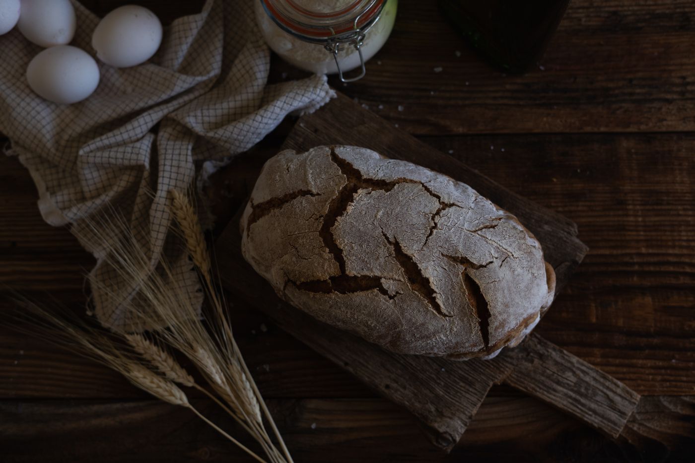 Rustic bread and wheat on a wooden table, illustrating hospitality and food.
