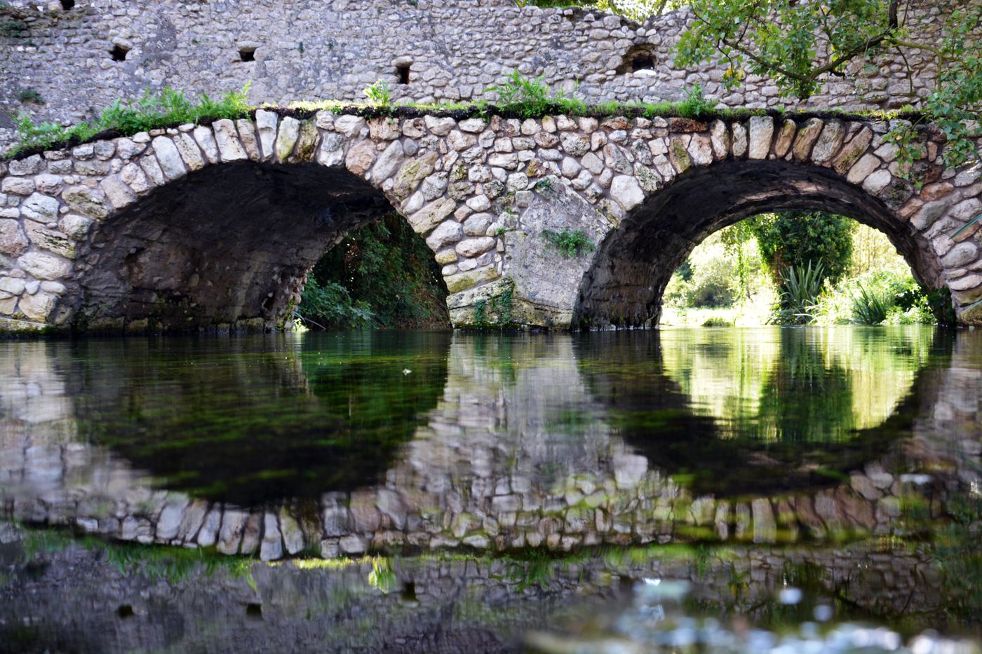 An old stone bridge reflected in water, illustrating control over a river crossing.