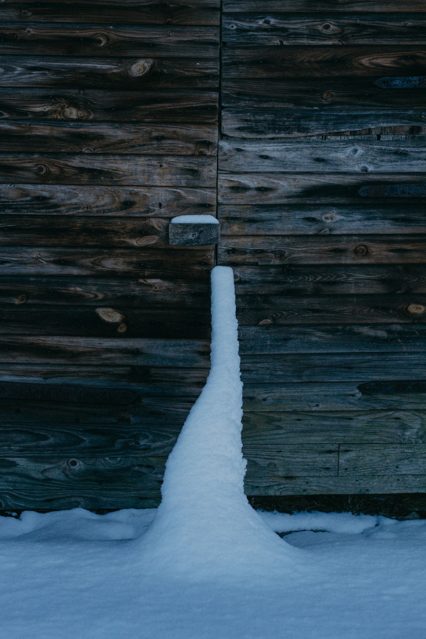 A weathered wooden doorway surrounded by snow, illustrating a winter boundary.