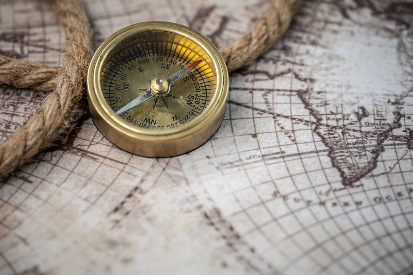 A brass compass and rope on an antique map; a thematic photograph, not a map of Westeros.