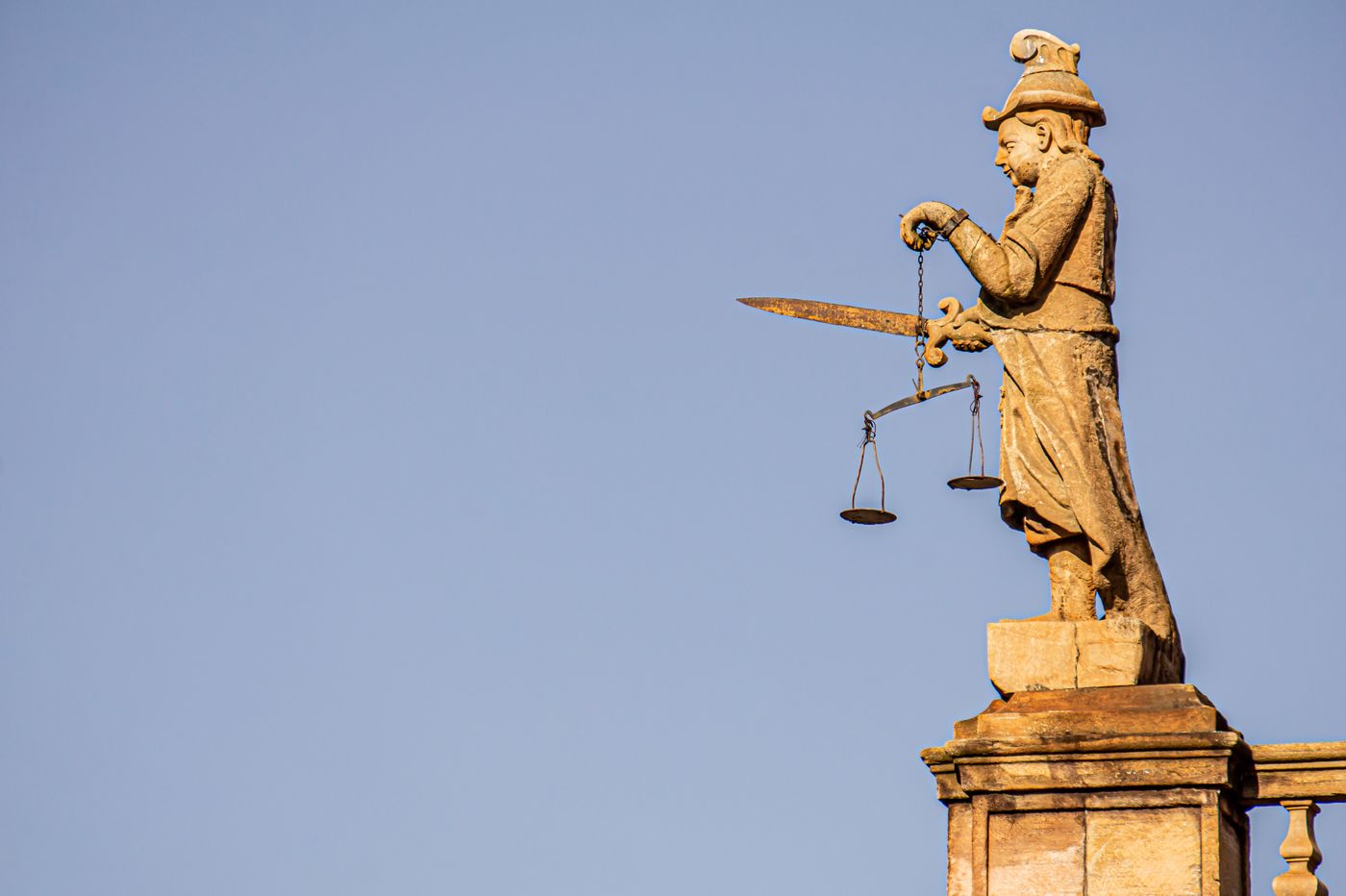 A justice statue holding a sword and balanced scales, illustrating judgement backed by force.