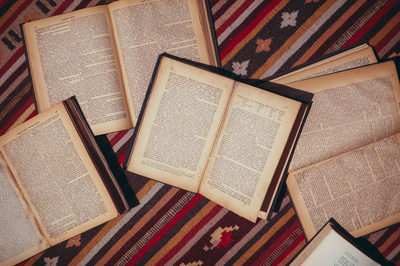 Vintage open books spread across patterned cloth, illustrating knowledge and reading.